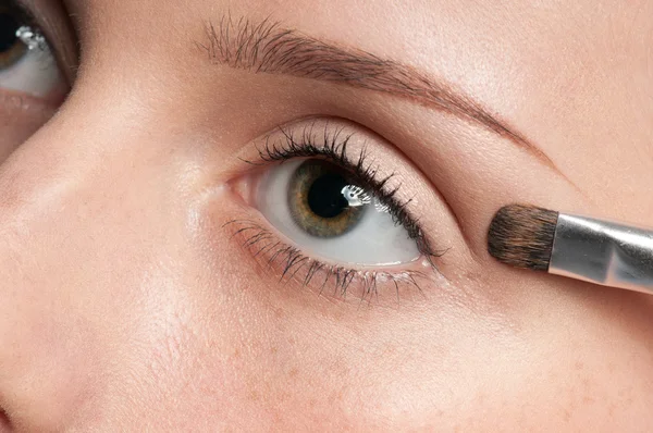 Mulher aplicando pincel de tinta cosmética na zona dos olhos — Fotografia de Stock