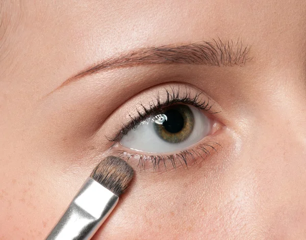 Mulher aplicando pincel de tinta cosmética na zona dos olhos — Fotografia de Stock