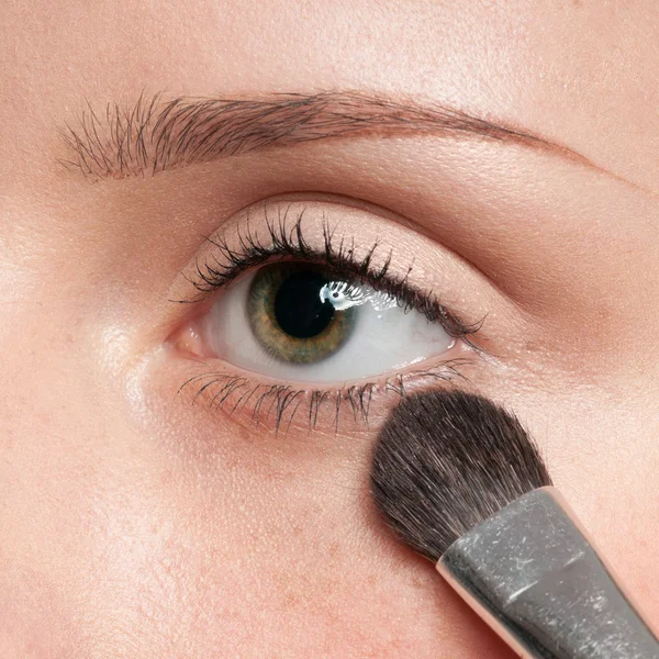 Kvinna tillämpa kosmetiska pensel på ögat zon — Stockfoto