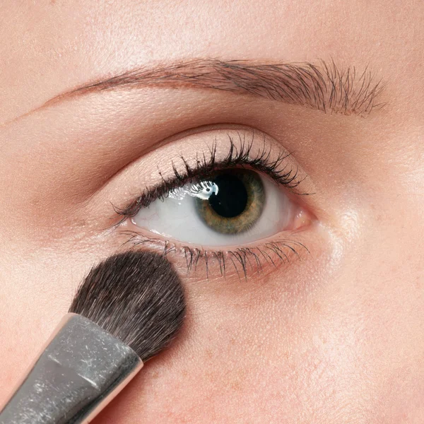 Vrouw cosmetische kwast toe te passen op oog zone — Stockfoto
