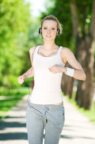 Νεαρή γυναίκα που τρέχει σε καταπράσινο πάρκο — Φωτογραφία Αρχείου