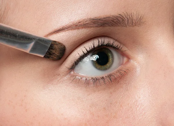 Femme appliquant un pinceau cosmétique sur la zone des yeux — Photo