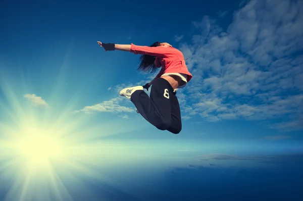 Donna sportiva che salta e vola sopra cielo e sole — Foto Stock