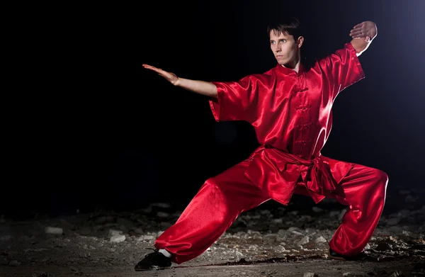 Человек Ушу в красном практикует мартиальное искусство — стоковое фото