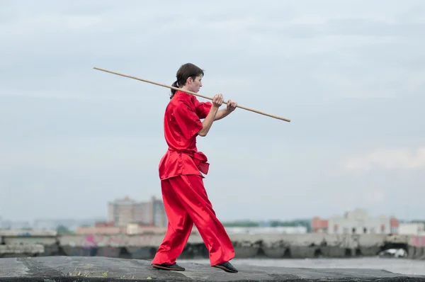 Человек Ушу в красном практикует мартиальное искусство — стоковое фото