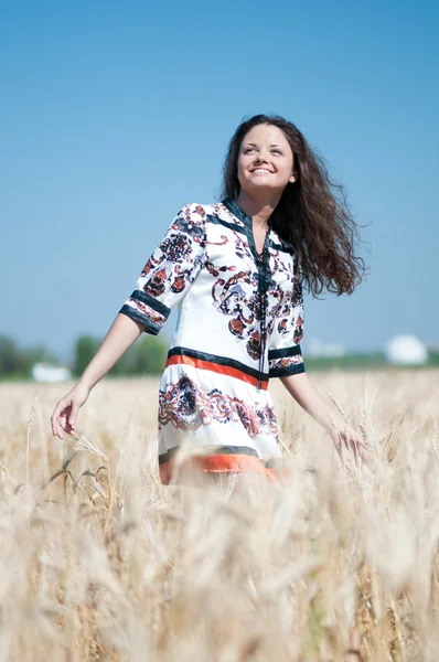 Piękna kobieta chodzić w polu pszenicy w słoneczny letni dzień. — Zdjęcie stockowe