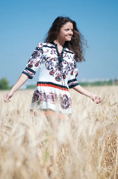 Mooie vrouw lopen in tarweveld op zonnige zomerdag. — Stockfoto
