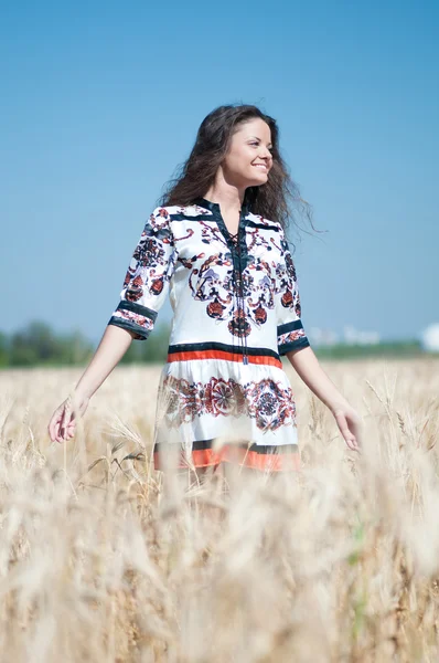 Hermosa mujer caminar en el campo de trigo en el soleado día de verano . —  Fotos de Stock