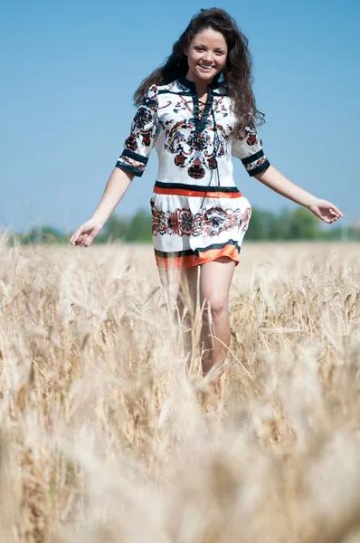 Mooie vrouw lopen in tarweveld op zonnige zomerdag. — Stockfoto