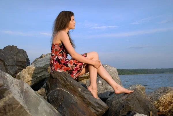 Menina sentar-se na rocha na costa do mar — Fotografia de Stock