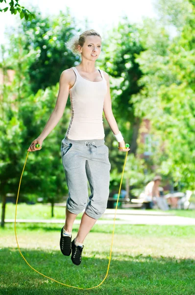 Mujer con saltar la cuerda en el parque Imagen de archivo