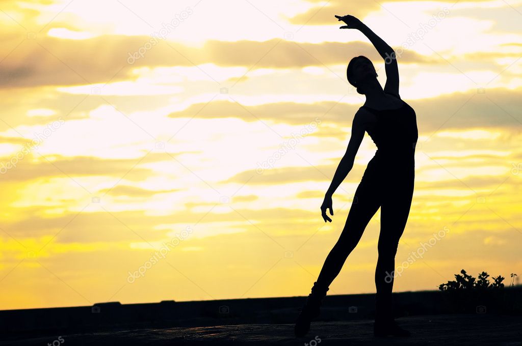 Silhouette of dancing woman over sunset. Yoga
