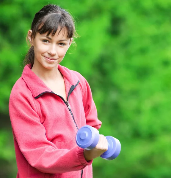 Девушка делает гантели упражнения на открытом воздухе — стоковое фото