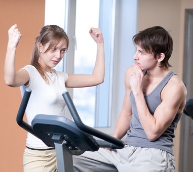 Train on machine in a gym assisted by personal instructor clipart