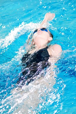 Swimmer in swim meet doing backstroke