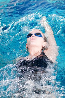 Swimmer in swim meet doing backstroke