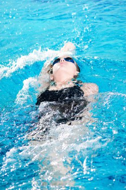 Swimmer in swim meet doing backstroke