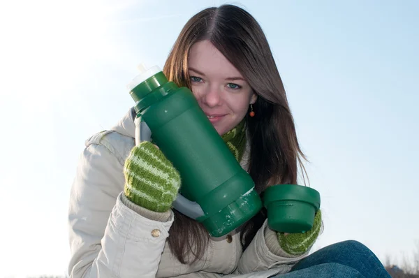 Девушка на зимнем пикнике с чашкой горячего тее и термосом — стоковое фото