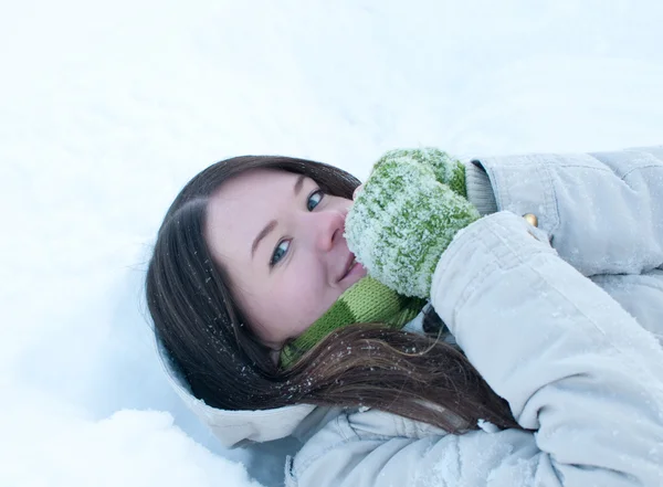 Beautiful girl in green lying in snow — Stock Photo, Image