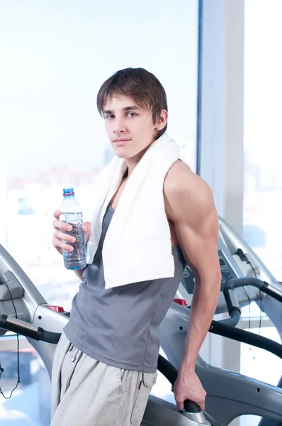 Man at the gym exercising. Run on on a machine and drink water — Stock Photo, Image