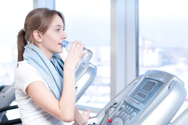Kobieta na siłowni, ćwiczenia. uruchomić na maszyny i napił się wody — Zdjęcie stockowe
