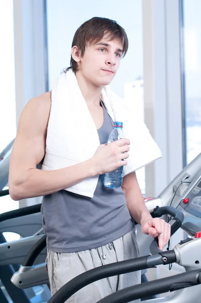 Muž v tělocvičně cvičení. spustit na stroj a pít vodu — Stock fotografie