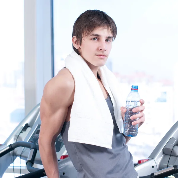 Man at the gym exercising. Run on on a machine and drink water — Stock Photo, Image