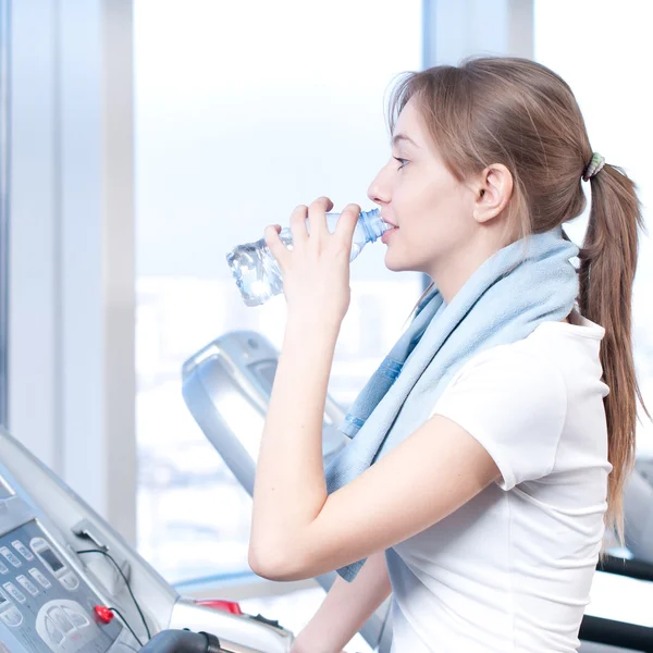 Woman at the gym exercising. Run on on a machine and drink water — Stock Photo, Image