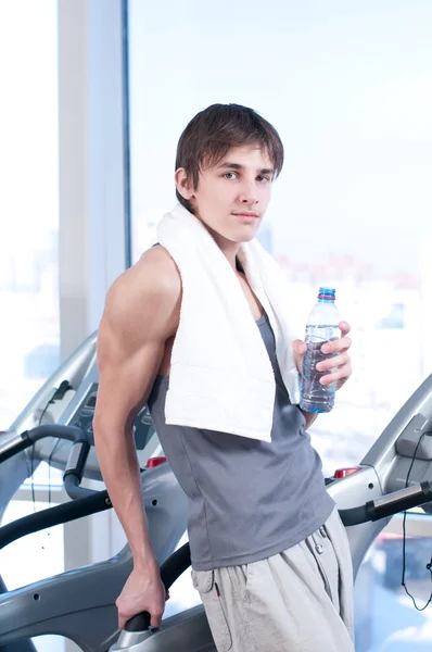 Hombre en el gimnasio haciendo ejercicio. Correr en una máquina y beber agua —  Fotos de Stock