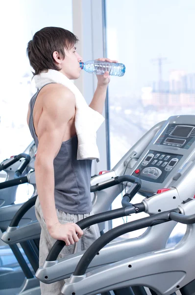 Мужчина в спортзале пьет воду — стоковое фото