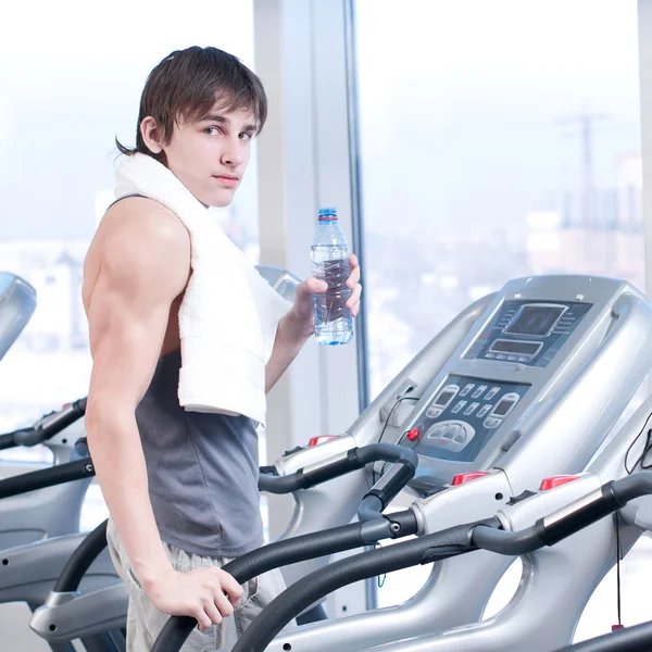 Homem no ginásio a exercitar-se. Corra em uma máquina e beba água — Fotografia de Stock