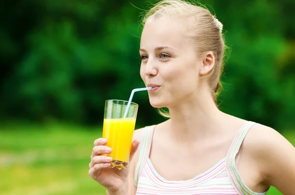 Молодая женщина пьет апельсиновый сок. На открытом воздухе — стоковое фото