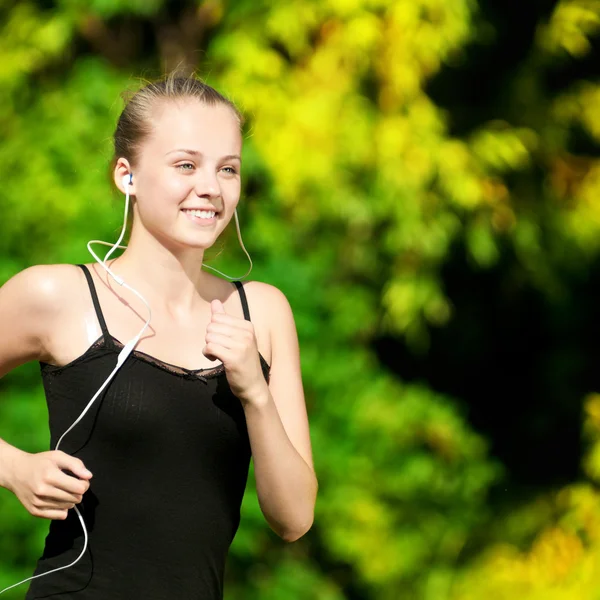 Молода жінка біжить у зеленому парку — стокове фото