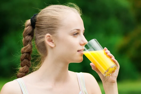 오렌지 주스를 마시는 젊은 여자. 야외 — 스톡 사진