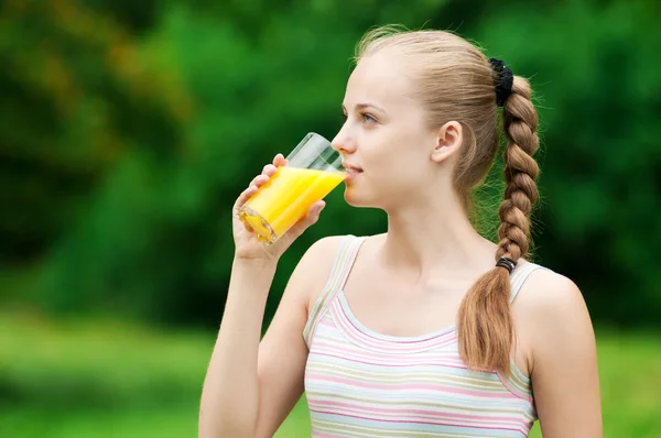 Genç bir kadın portakal suyu içiyor. Açık — Stok fotoğraf