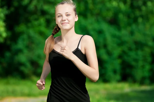 Молодая женщина бегает в зеленом парке — стоковое фото