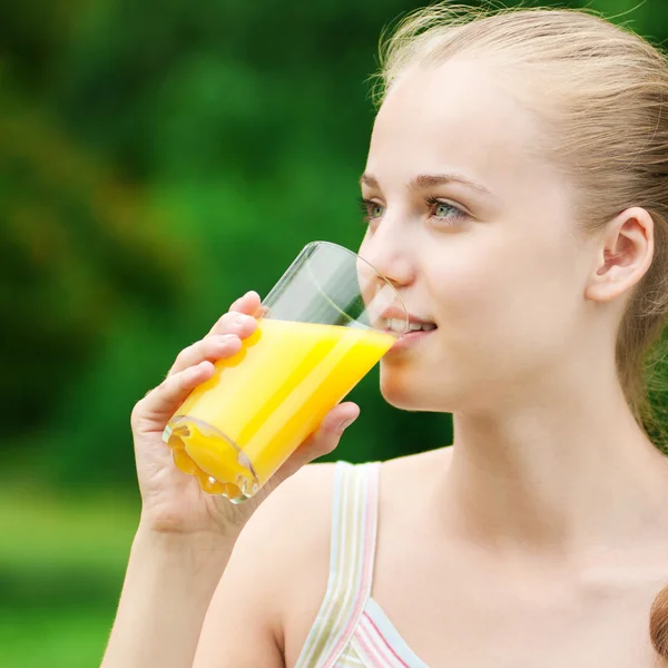 Jovem mulher bebendo suco de laranja. Ao ar livre — Fotografia de Stock