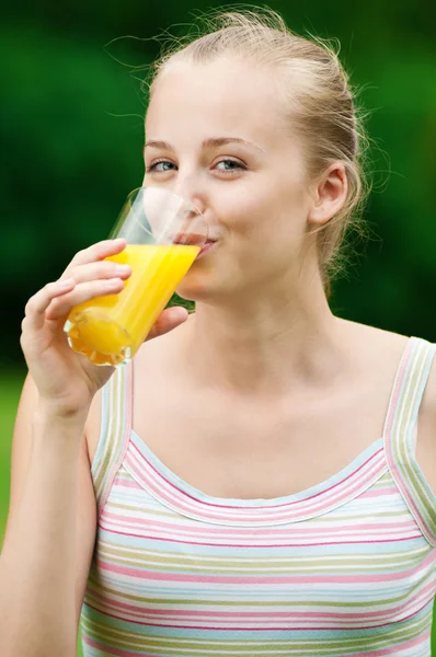 Ung kvinna dricker apelsinjuice. utomhus — Stockfoto