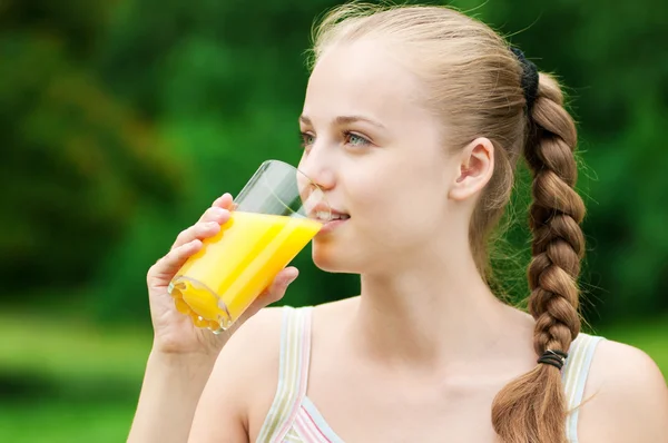 Jovem mulher bebendo suco de laranja. Ao ar livre — Fotografia de Stock