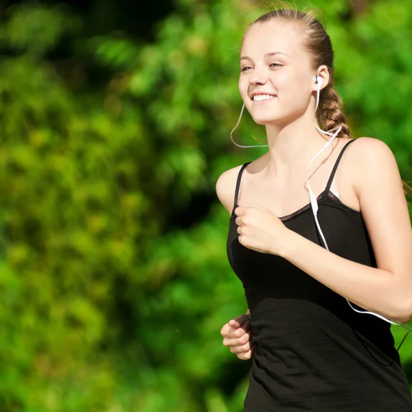 Молодая женщина бегает в зеленом парке — стоковое фото