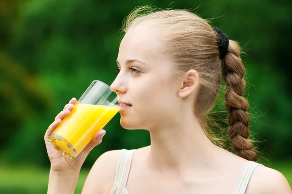 Mladá žena pije pomerančovou šťávu. venkovní — Stock fotografie