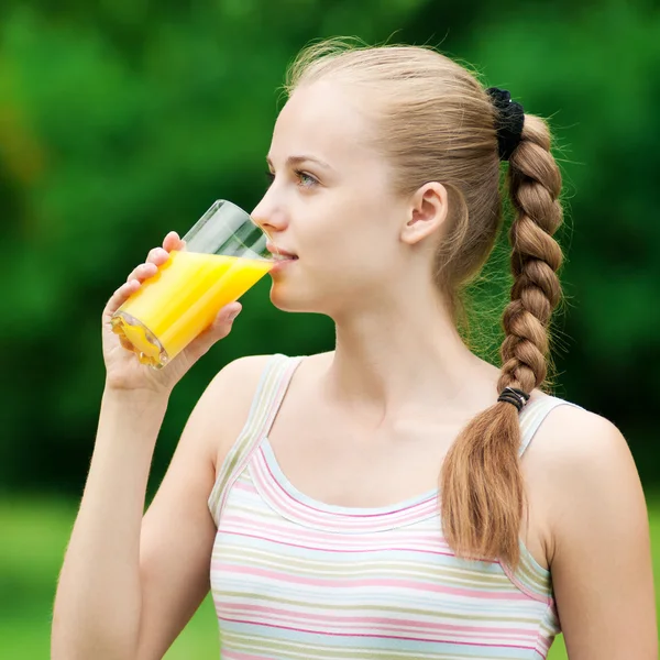 若い女性はオレンジ ジュースを飲みます。屋外 — ストック写真