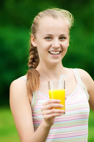 Ung kvinna dricker apelsinjuice. utomhus — Stockfoto