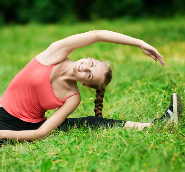 Genç bir kadın esneme egzersizi yapıyor. — Stok fotoğraf