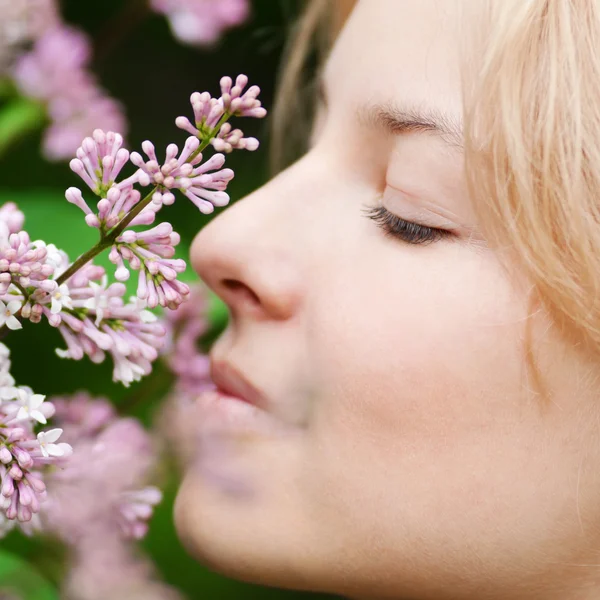 Жінка з бузковою квіткою на обличчі — стокове фото