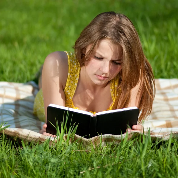 Dışarıda kitap okuyan güzel genç bir kadın. — Stok fotoğraf