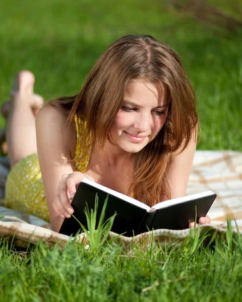 Dışarıda kitap okuyan güzel genç bir kadın. — Stok fotoğraf