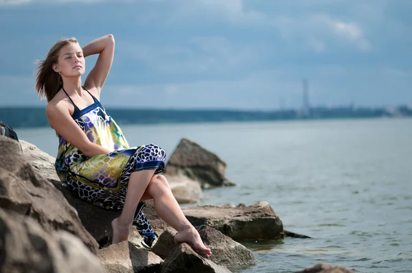 Sad woman in dress sitting on rock — Stock Photo, Image