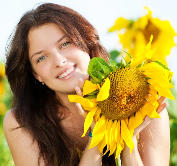 Vacker kvinna i en solros fält — Stockfoto