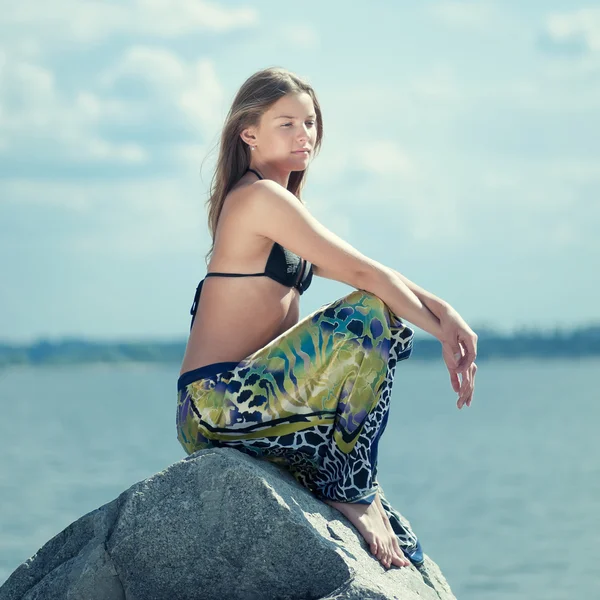 Schöne Frau entspannt sich auf einem Felsen über dem Meer — Stockfoto